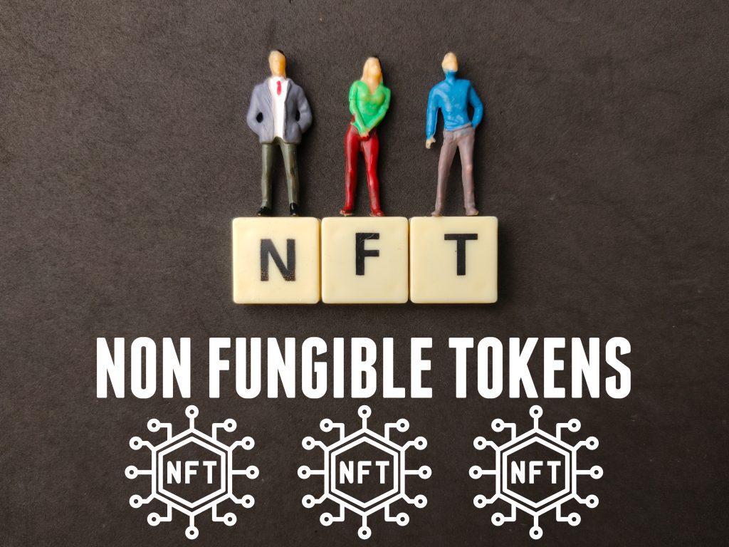 Miniature people,toys word and icon with text NFT (NON FUNGIBLE TOKENS) on black background.