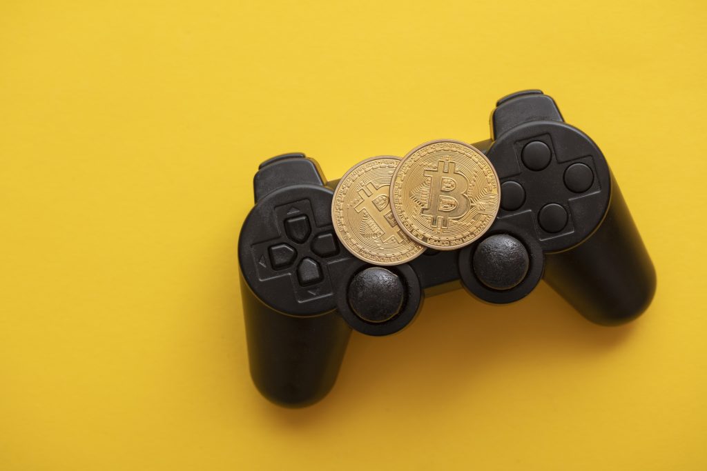 Concepto de juegos criptográficos. Controlador de videojuegos con una moneda de criptomoneda bitcoin. Los jugadores pueden ganar fácilmente de forma gratuita en los juegos con el futuro Free-to-Earn