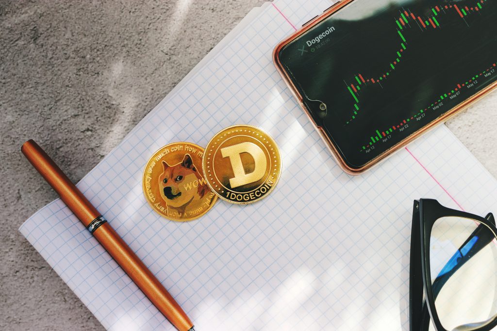 Dogecoin with mobile phone, diagram, growth graph on the screen, on the background of a notebook top view