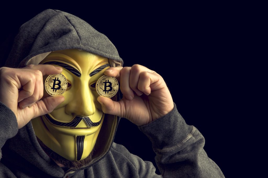 Hacker old bitcoin coin and wear anonymus mask .