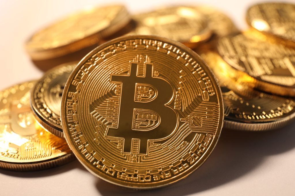 Shiny gold bitcoins on light background, closeup view. Digital currency