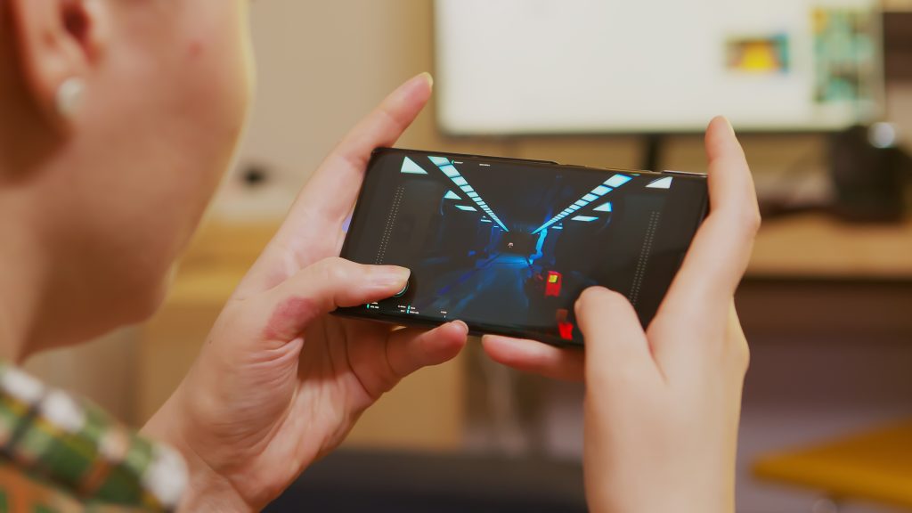 Back view of woman playing shooter games on smartphone. How to Improve Performance on Low-End Android Phones