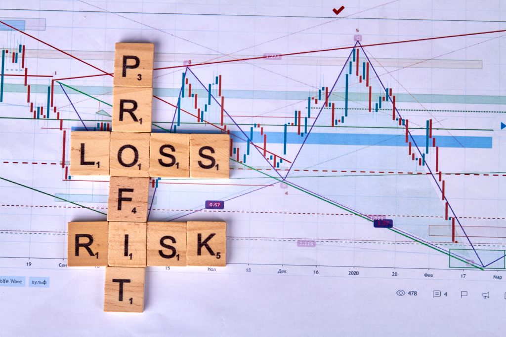 Wooden cubes with profit risk and loss words. Statistic graph diagram on the background. 