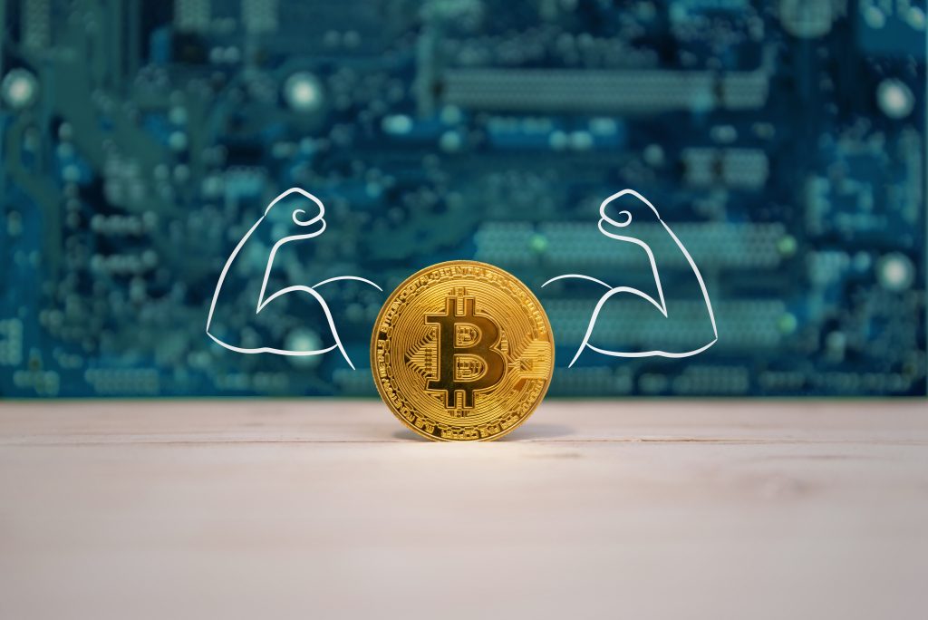 Strong bitcoin with tense muscles in the arms concept. Electronic in background